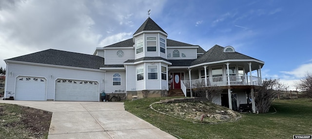 victorian-style house featuring a front lawn, a shingled roof, covered porch, concrete driveway, and an attached garage