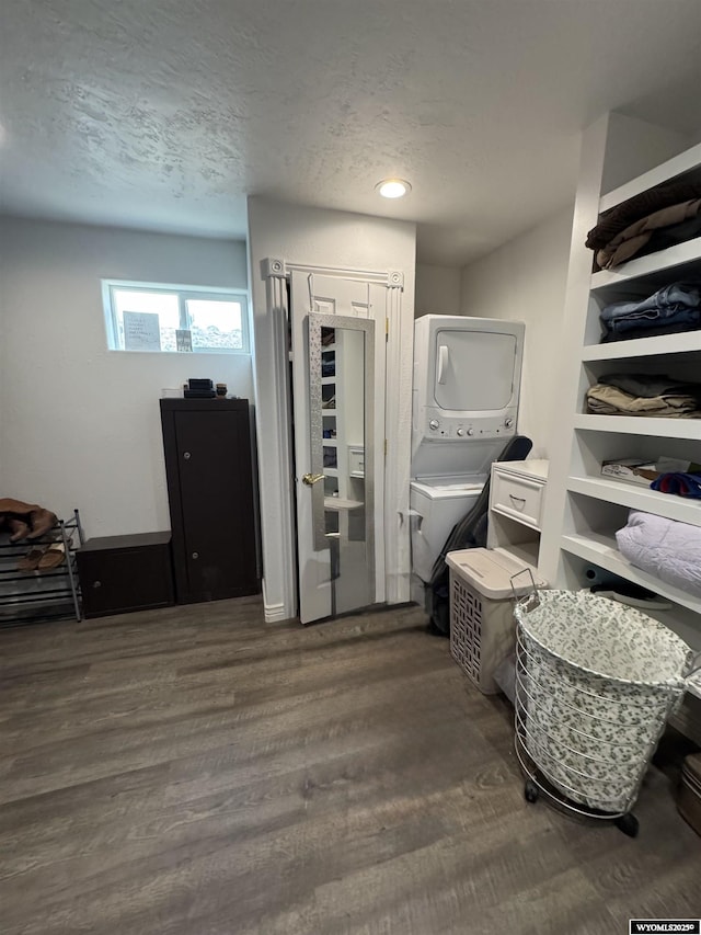 interior space with recessed lighting, stacked washer and clothes dryer, a textured ceiling, and wood finished floors