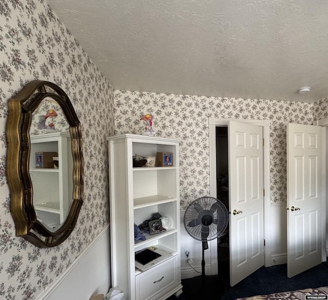 bedroom featuring wallpapered walls and a textured ceiling