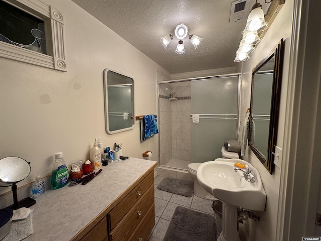 bathroom with a textured ceiling, a shower stall, a sink, toilet, and tile patterned flooring