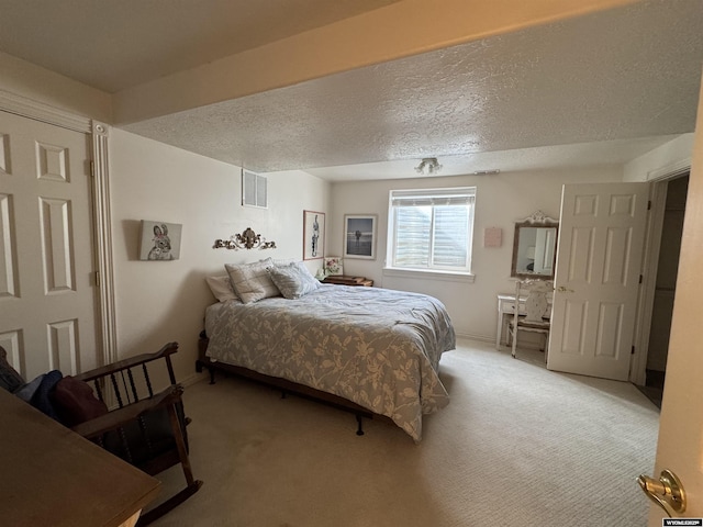 bedroom featuring baseboards, visible vents, light carpet, and a textured ceiling