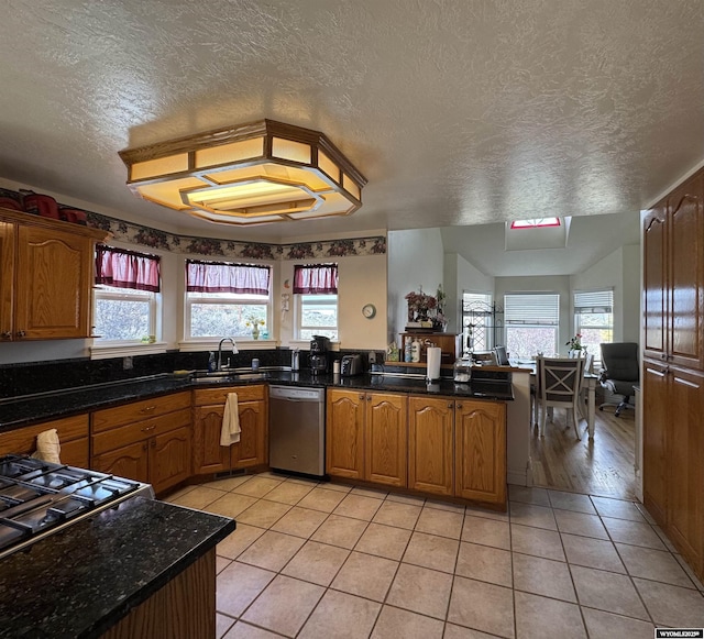 kitchen with a textured ceiling, dishwasher, a peninsula, and a sink