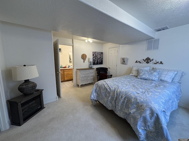 bedroom featuring light colored carpet, visible vents, and a textured ceiling