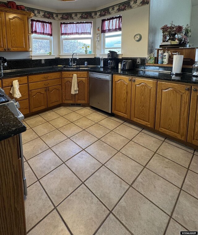 kitchen with a healthy amount of sunlight, stainless steel dishwasher, brown cabinetry, and a sink
