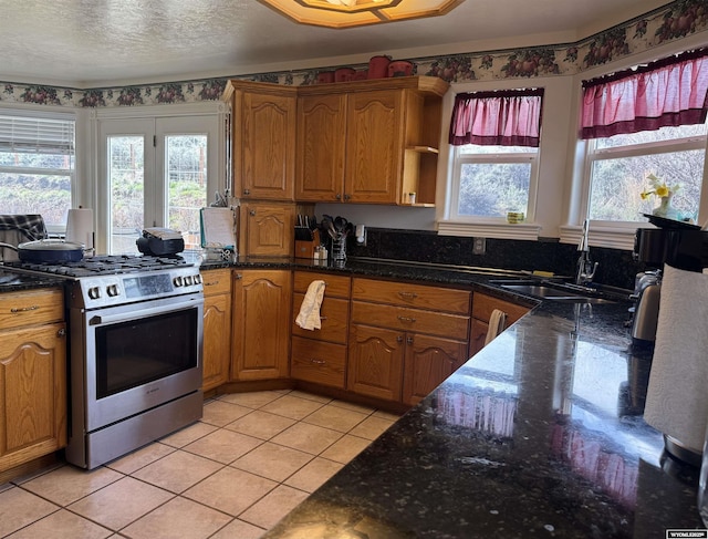 kitchen featuring stainless steel range with gas cooktop, light tile patterned floors, plenty of natural light, and a sink