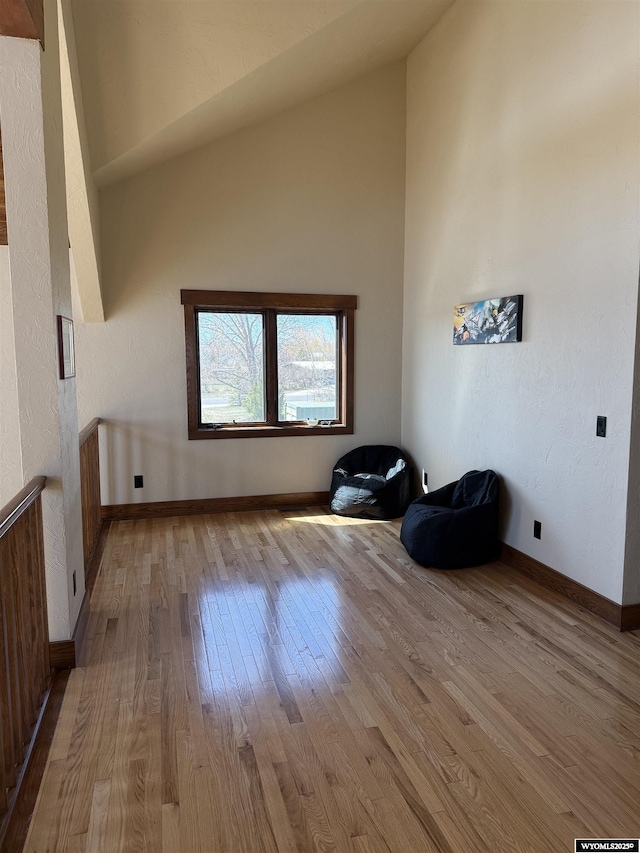 interior space with hardwood / wood-style floors, high vaulted ceiling, and baseboards