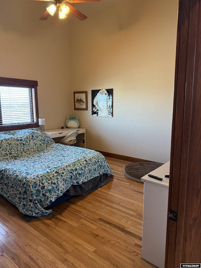 bedroom featuring ceiling fan, light wood-style flooring, and baseboards