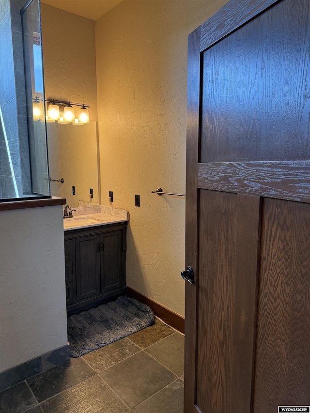bathroom featuring baseboards, vanity, and stone finish flooring