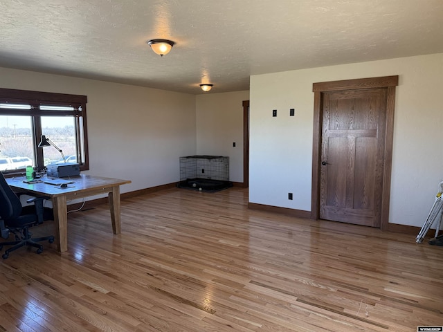office space with light wood finished floors, a textured ceiling, and baseboards