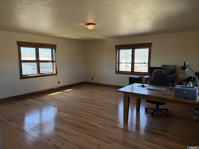 unfurnished office with a textured ceiling, wood finished floors, and baseboards
