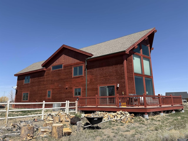 back of house featuring fence, a deck, and a shingled roof