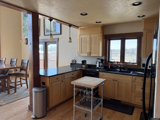 kitchen featuring a sink, light brown cabinets, a peninsula, a textured ceiling, and dishwasher