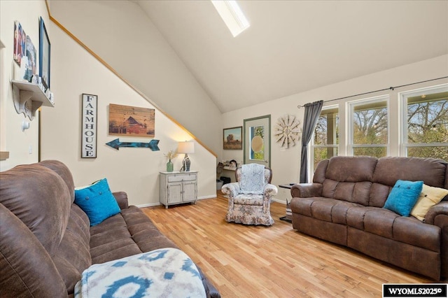 living area featuring wood finished floors, high vaulted ceiling, and baseboards