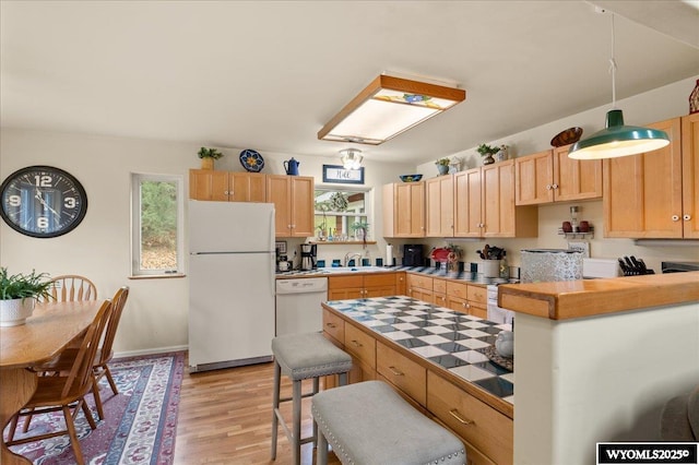 kitchen with light wood-style flooring, a sink, tile counters, light brown cabinetry, and white appliances