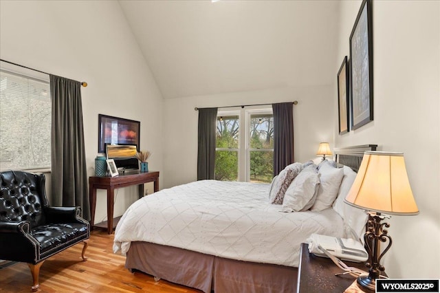bedroom featuring high vaulted ceiling and wood finished floors