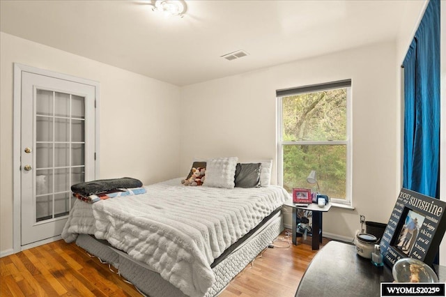 bedroom with visible vents, wood finished floors, and baseboards