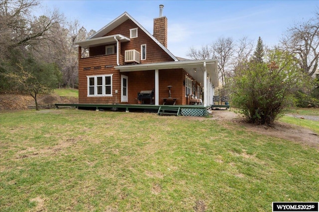 back of property with a chimney, a balcony, a yard, and central air condition unit