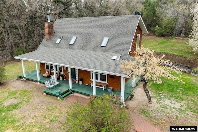back of house with a chimney and roof with shingles
