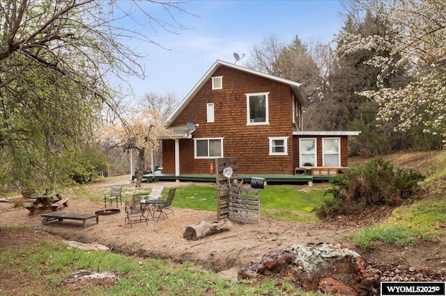 back of property with a deck and a fire pit