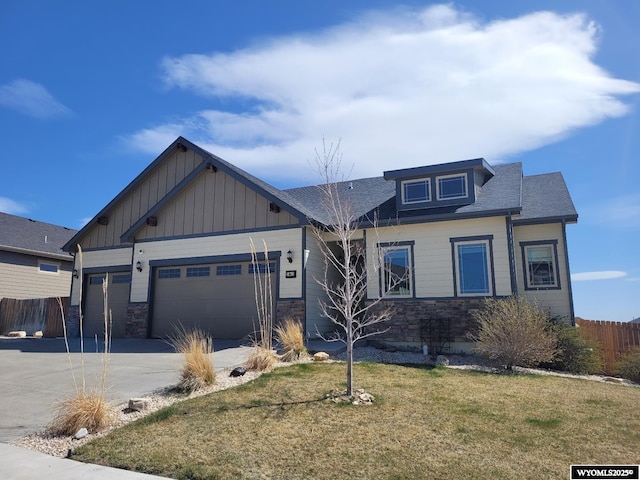 craftsman-style home featuring board and batten siding, fence, stone siding, concrete driveway, and an attached garage