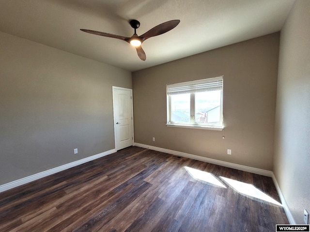 spare room featuring a ceiling fan, baseboards, and dark wood finished floors