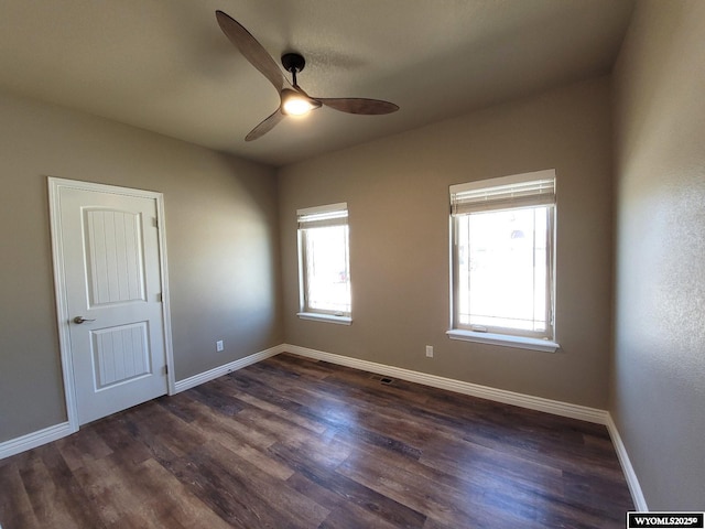 spare room featuring baseboards, a ceiling fan, and dark wood-style flooring