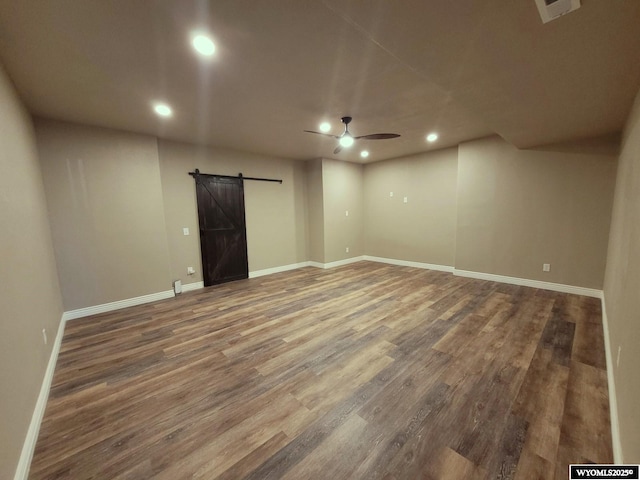 below grade area with a barn door, ceiling fan, recessed lighting, and baseboards