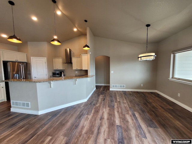 kitchen featuring high end refrigerator, visible vents, exhaust hood, and arched walkways