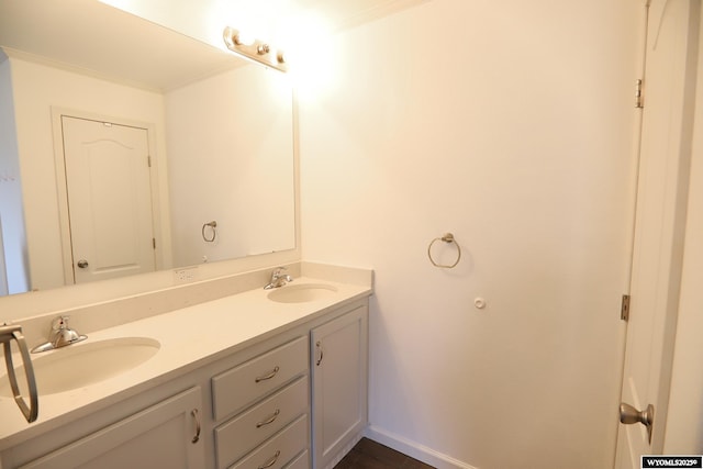 full bathroom with double vanity, a sink, baseboards, and crown molding