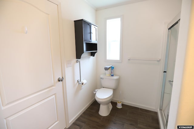 bathroom with toilet, baseboards, wood finished floors, a shower with door, and ornamental molding
