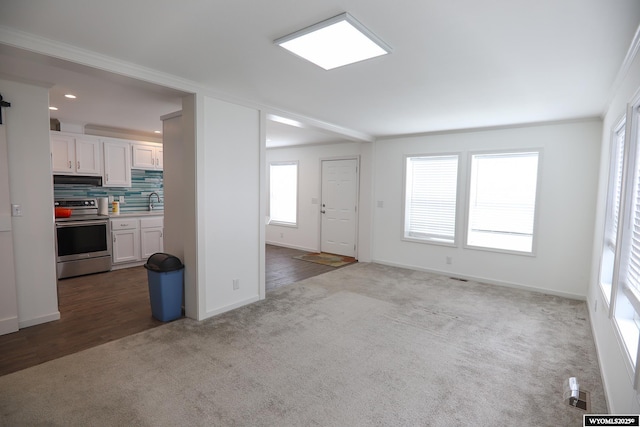 unfurnished living room featuring dark colored carpet, baseboards, and visible vents