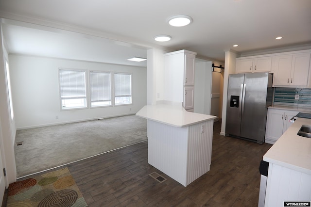 kitchen featuring white cabinets, a barn door, light countertops, stainless steel refrigerator with ice dispenser, and visible vents