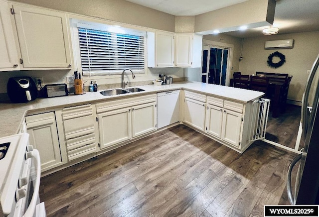 kitchen featuring dark wood-style flooring, white dishwasher, a sink, gas stove, and white cabinets