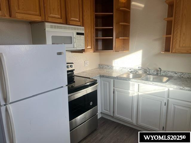 kitchen featuring open shelves, a sink, white appliances, light countertops, and dark wood-type flooring