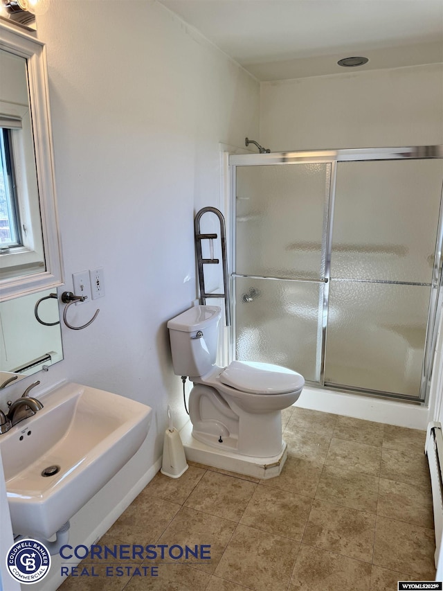 bathroom with toilet, a baseboard heating unit, a sink, and a stall shower