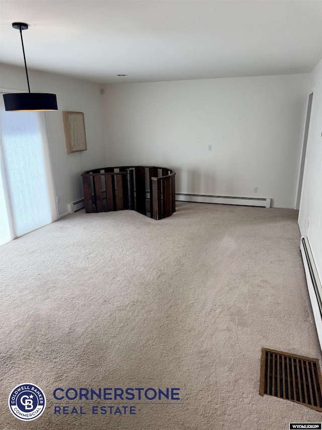 unfurnished room with carpet floors, visible vents, and baseboard heating