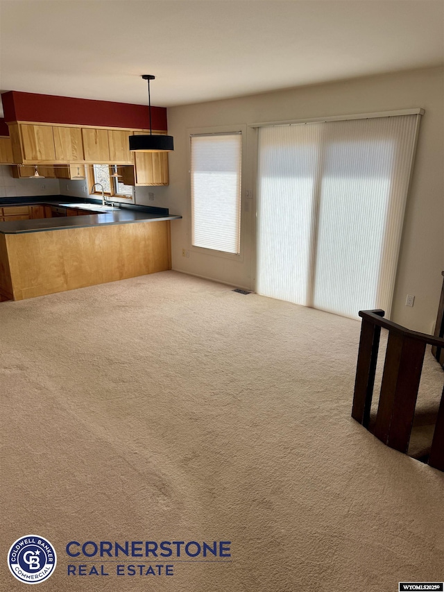 kitchen with a sink, dark countertops, carpet flooring, and visible vents