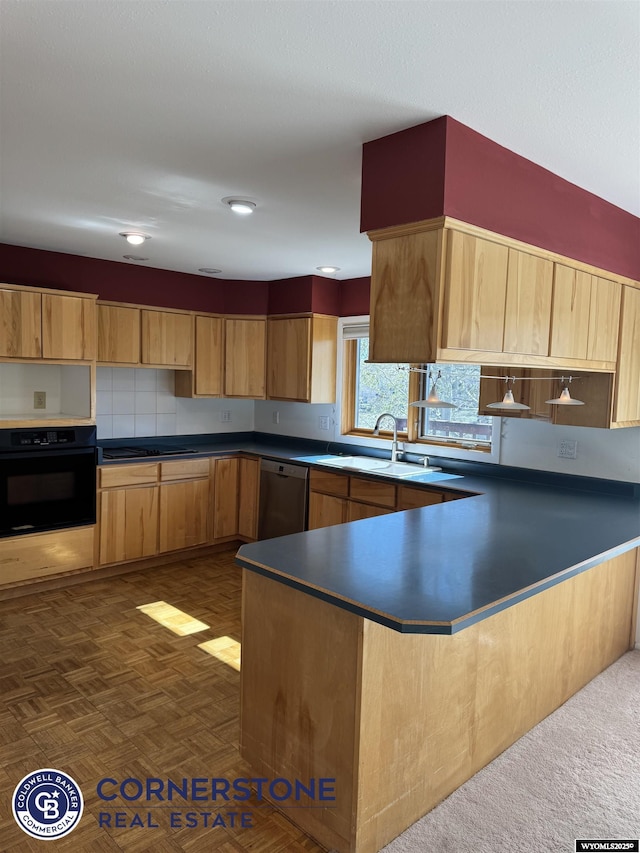 kitchen featuring dark countertops, a sink, black oven, a peninsula, and stainless steel dishwasher