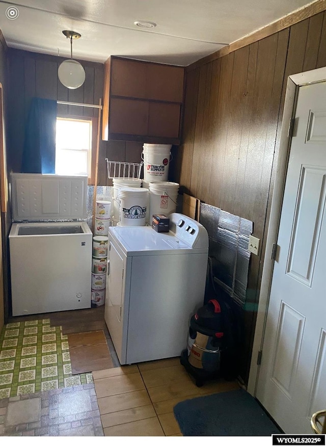 washroom featuring wooden walls, independent washer and dryer, laundry area, and light wood-type flooring