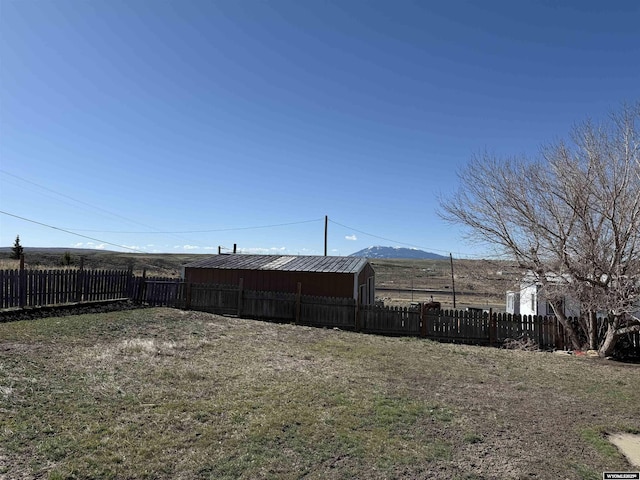 view of yard featuring fence, an outbuilding, and a mountain view