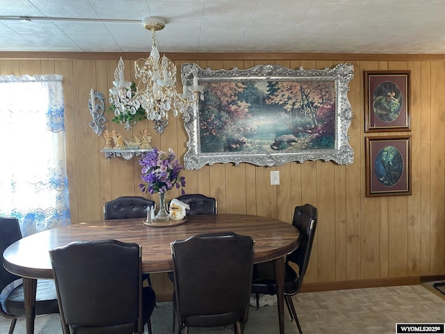 dining room featuring baseboards, wood walls, and a notable chandelier