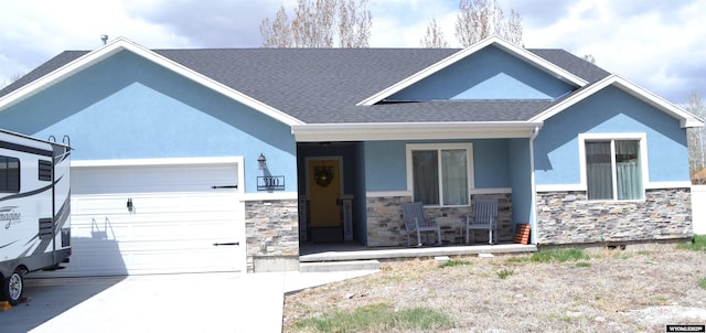 view of front of home with covered porch, driveway, an attached garage, stone siding, and stucco siding