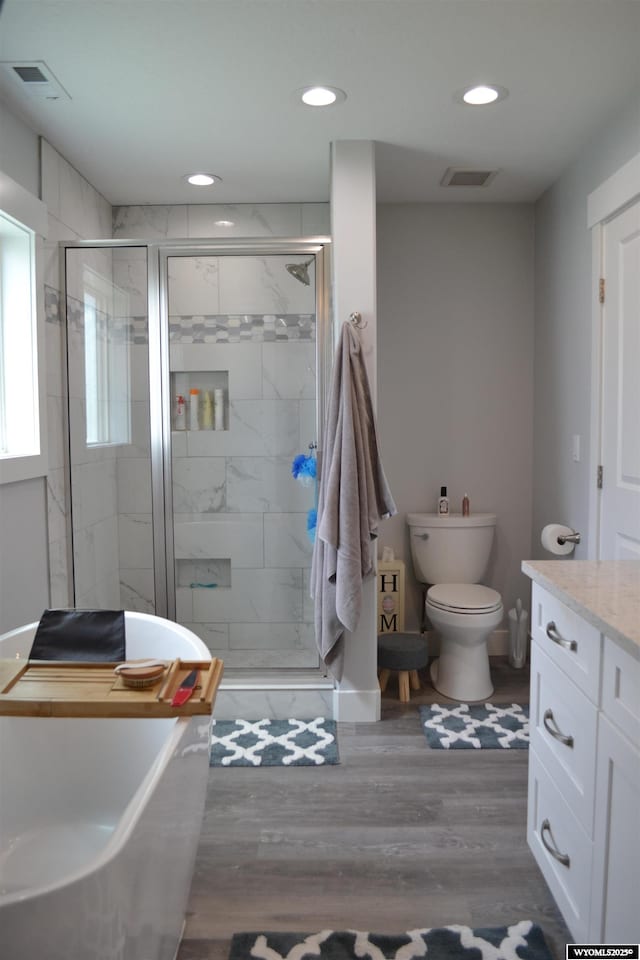 bathroom with visible vents, a stall shower, wood finished floors, vanity, and toilet