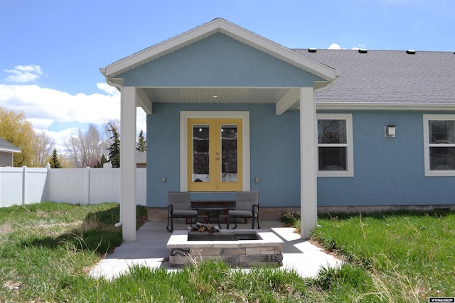 rear view of house with french doors, roof with shingles, fence, an outdoor fire pit, and stucco siding