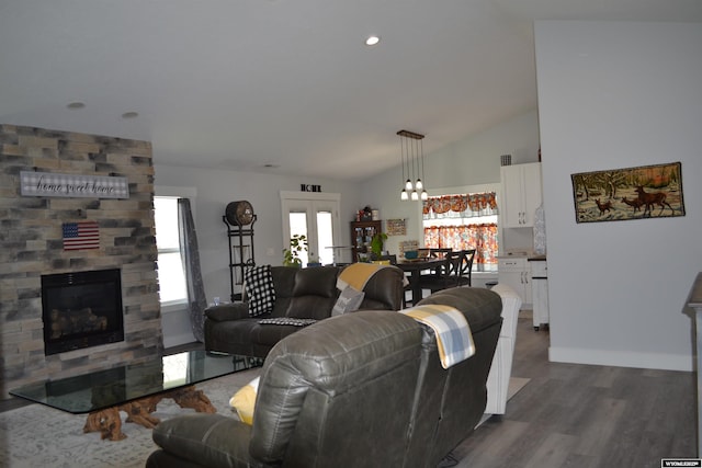 living area with french doors, dark wood-style flooring, a large fireplace, baseboards, and lofted ceiling