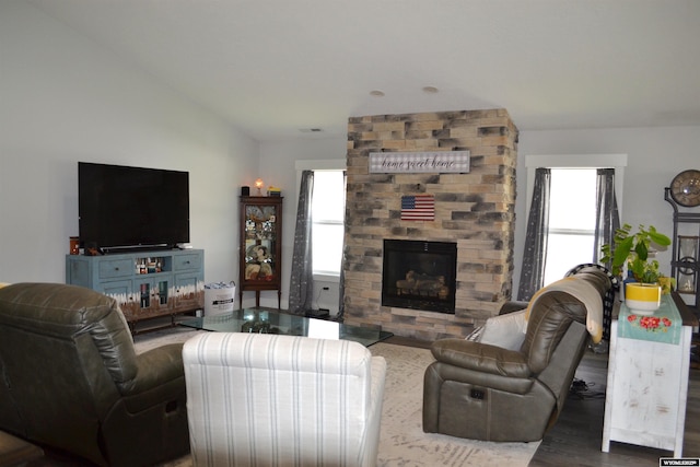living room with vaulted ceiling, a large fireplace, a healthy amount of sunlight, and wood finished floors