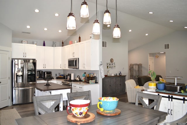 kitchen with white cabinets, appliances with stainless steel finishes, dark wood-type flooring, a kitchen island, and visible vents