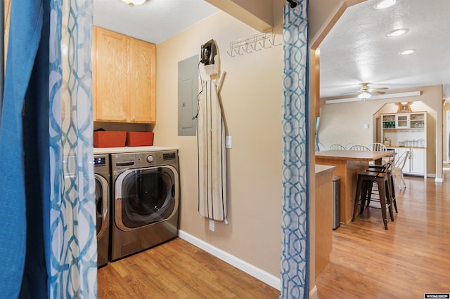 washroom with cabinet space, ceiling fan, light wood-style floors, baseboards, and washer and clothes dryer