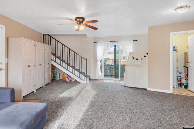 unfurnished living room with baseboards, a ceiling fan, carpet flooring, and stairs