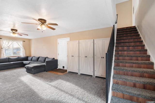carpeted living area featuring a ceiling fan and stairs